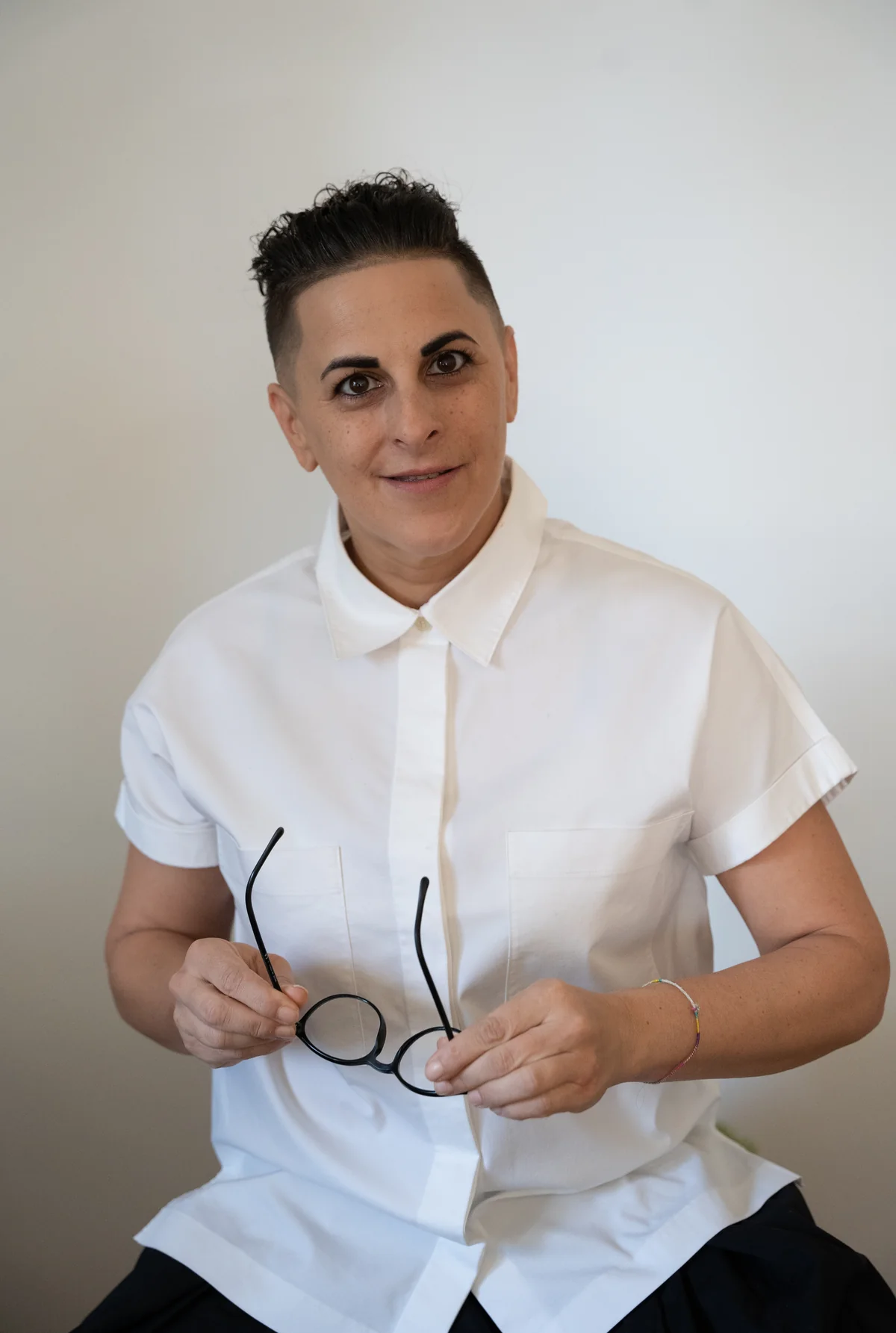 Silvia Buchinger im weißen Oberteil, mit einer Brille in den Händen